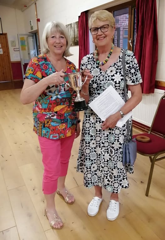 Two ladies holding a goblet cup nammed the Ailwyn Cup